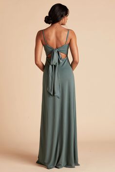 the back of a woman wearing a long green dress with a bow at the waist