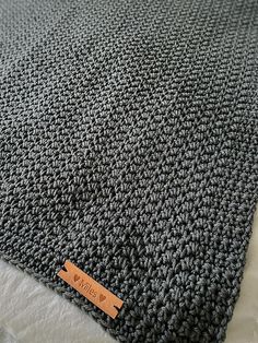 a close up of a knitted blanket with a tag on the bottom of it