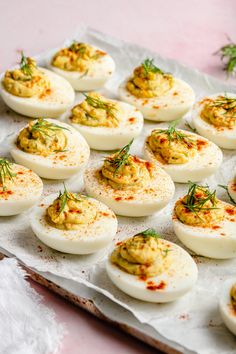 deviled eggs are arranged on a baking sheet with herbs sprinkled on top