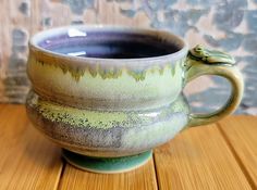 a green and gray cup sitting on top of a wooden table