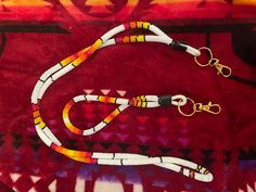 two leashes are laying on top of a red and white blanket with gold hardware