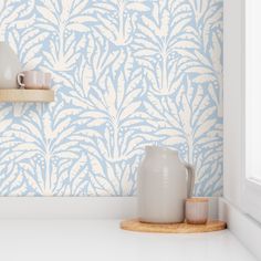 a blue and white wallpaper in a kitchen with two cups on the counter top