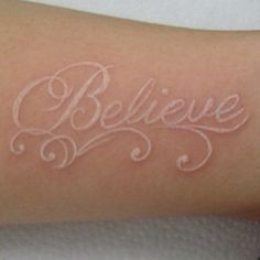 a woman's arm with the word believe written on it in cursive writing