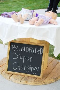 a sign that says blindfold diaper changing on top of a table with stuffed animals