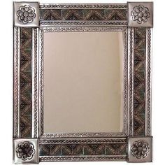 an ornate silver frame mirror with flowers on the sides and a flower decoration around the edges