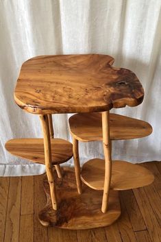 three tiered wooden table with white curtains in the backgroung area and wood flooring