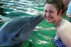 a woman is kissing a dolphin in the water