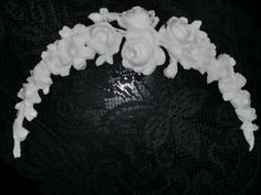 there is a white flower headband on the black tablecloth with it's flowers