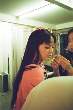 a woman is looking at her cell phone while another person looks on in the mirror