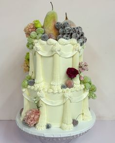 a three tiered cake with fruit and flowers on top