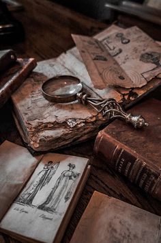 an old book and magnifying glass sitting on top of a table next to other books