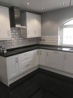 an empty kitchen with white cabinets and black counter tops in the middle of the room