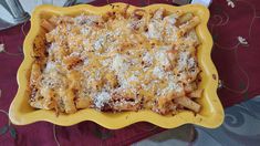 a casserole dish with pasta and cheese in it on a red table cloth