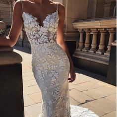 a woman in a white wedding dress standing on the street with her hand on her hip