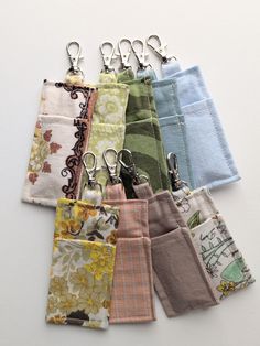 several different types of cloths hanging from hooks on a white surface with clippings attached to them