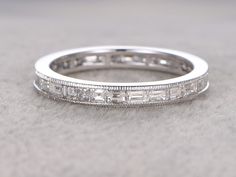 a white gold wedding band with baguetts set in the center on a gray surface