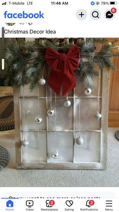 an old window is decorated for christmas with ornaments and a bow on the front door