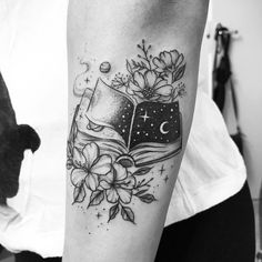 a black and white photo of a book with flowers on it's arm, next to a clock