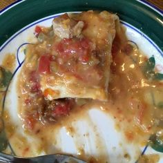 a green and white plate topped with lasagna covered in sauce, meat and cheese