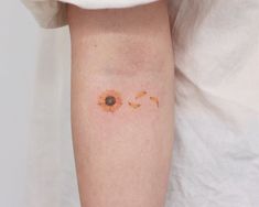 a small sunflower tattoo on the right arm and leg, with an orange flower in it's center