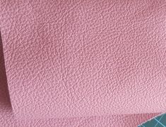 two pieces of pink leather sitting next to each other on top of a blue table