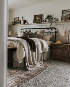 a bedroom with a bed, nightstands and pictures on the wall above it is shown