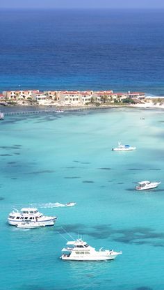 several boats floating in the ocean near a small island with houses and buildings on it