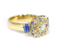 This custom designed wedding ring was redesigned from an older wedding ring and tanzanite fashion ring. The stones were removed and reset into the new halo style ring. A few tanzanite gemstones were added alternating the diamonds around the halo. DETAILS Material: 14-karat yellow gold Main Stone: 75-carat round brilliant cut diamond 1.25cttw diamonds Genuine round and emerald-cut tanzanites Measurements: 13.8mm halo width, 4.5mm band width Wedding Halo Ring With Tanzanite In Halo Setting, Anniversary Tanzanite Halo Ring, Tanzanite Diamond Ring With Halo Setting As Gift, Tanzanite Halo Design Ring For Gift, Gold Tanzanite Ring With Halo Setting, Yellow Gold Tanzanite Diamond Ring With Halo Setting, Luxury Tanzanite Diamond Ring With Halo Setting, Diamond Halo Ring, Tanzanite Gemstone