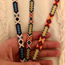 three bracelets in different colors and designs are being held by someone's hand