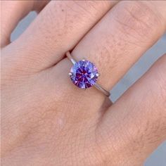 a woman's hand with a ring on it and a purple stone in the middle