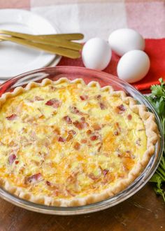 an egg and bacon quiche in a pie pan on a table with other ingredients