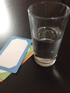 a shot glass and coasters sitting on a black table with a name tag next to it