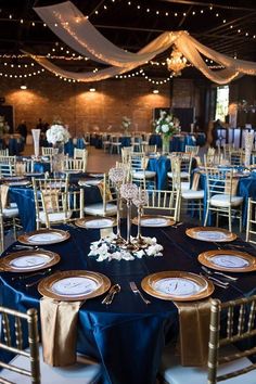 the tables are set up with blue and gold linens for an elegant wedding reception