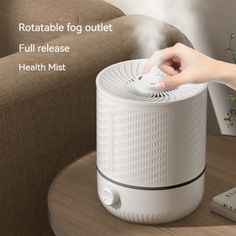 an air purifier sitting on top of a table next to a remote control