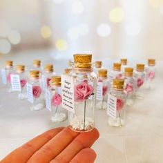 a hand holding a tiny bottle filled with pink roses and small bottles full of white flowers