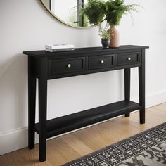 a black console table with two drawers and a mirror on the wall in front of it