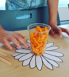 a plastic cup filled with cereal sitting on top of a wooden table