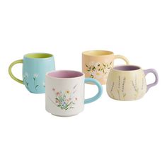 four different colored mugs with flowers painted on the inside and outside of each cup