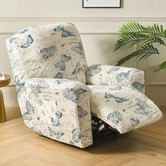 a recliner chair sitting on top of a hard wood floor next to a potted plant