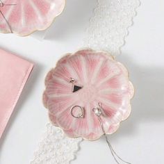 two pink plates with rings on them next to a lace doily and an envelope