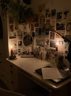 a desk with many pictures on the wall and a candle lit up in front of it