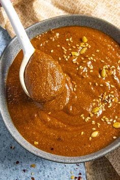 a spoon in a bowl filled with peanut sauce