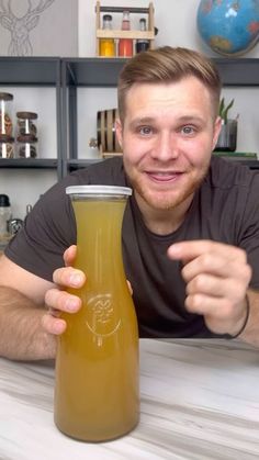 a man sitting at a table with a bottle of liquid