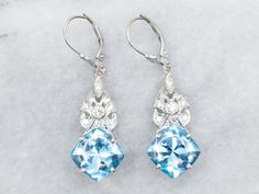 These stunning white gold drop earrings are sure to make a splash! Their shimmering blue topaz stones and diamond accents give them a look that's both dazzling and daring. Treat yourself to glitz and glamour--you deserve it! Metal: 14K White Gold Gem: 2 Blue Topaz totaling 14.40 Carats Gem Measurements: 10.7 mm, Square Cushion Cut Accents: Diamonds totaling .38 Carats, VS in Clarity, G-H in Color Measurements: 13.0 x 44.0 mm Marks: "14K:" Stamped on the findings SKU #: A30470 Each piece has been White Gold Drop Earrings, Blue Topaz Stone, Blue Topaz Earrings, Topaz Earrings, Diamond Drop Earrings, Topaz Stone, Diamond Drops, Earrings Blue, Gold Drop Earrings