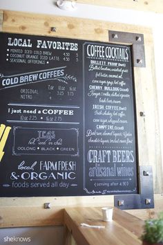 the menu on the wall is written in chalk and has different types of coffees