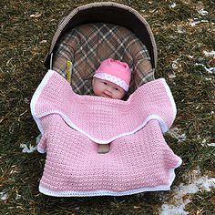 a baby in a car seat with a pink blanket on it's back and a pink hat on its head