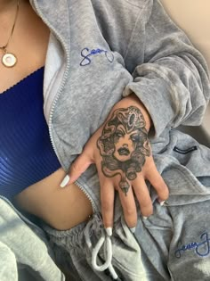 a woman's hand with tattoos on her left arm and the other half of her body covered in sweatpants