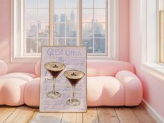 two martini glasses sitting on top of a wooden floor next to a pink couch in front of a window