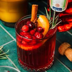 a cranberry apple cider is garnished with rosemary