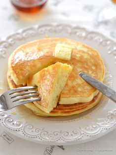 pancakes with butter and syrup are on a white plate next to a knife and fork